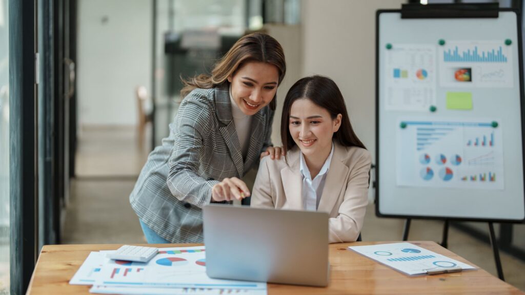 Dos trabajadores revisando informes en laptop.